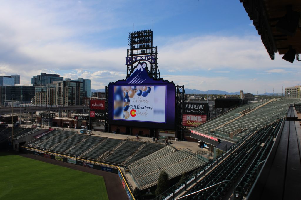 Coors Field scoreboard with the Rocky Mountains in the background.